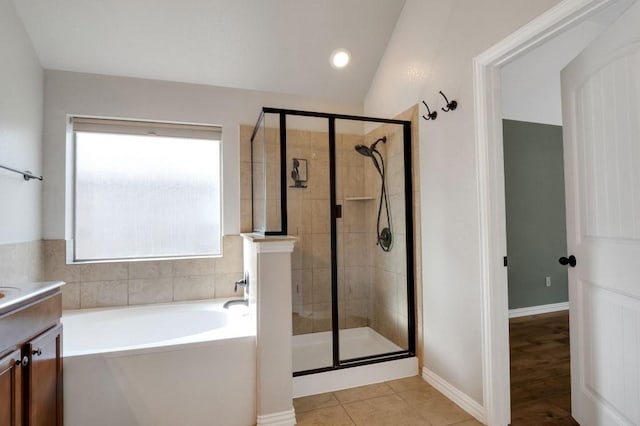 bathroom with tile patterned flooring, vanity, lofted ceiling, and plus walk in shower