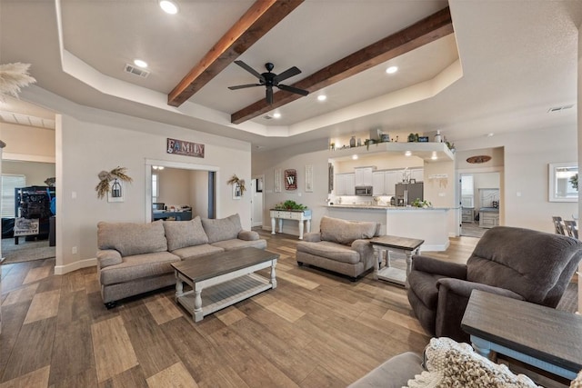 living room with beam ceiling, hardwood / wood-style flooring, and ceiling fan