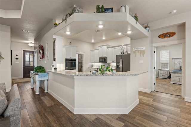 kitchen featuring light stone counters, appliances with stainless steel finishes, light hardwood / wood-style floors, and white cabinets