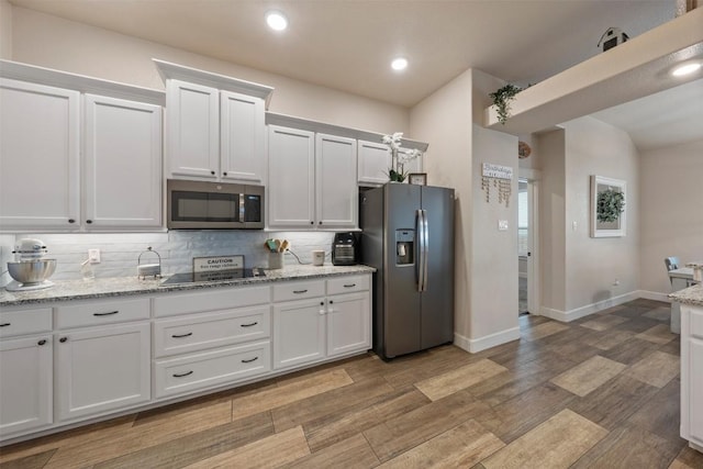 kitchen with white cabinetry, light stone counters, wood-type flooring, and appliances with stainless steel finishes