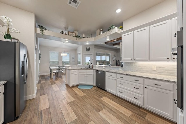 kitchen featuring white cabinetry, decorative light fixtures, kitchen peninsula, stainless steel appliances, and light hardwood / wood-style floors