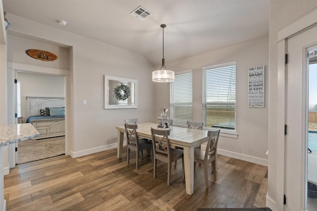 dining room featuring lofted ceiling and light hardwood / wood-style flooring