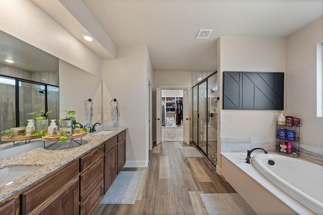 bathroom featuring vanity, plus walk in shower, and wood-type flooring