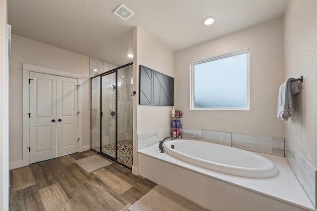 bathroom with hardwood / wood-style flooring and shower with separate bathtub