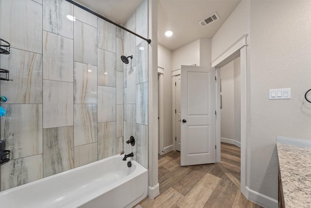 bathroom with tiled shower / bath, hardwood / wood-style floors, and vanity