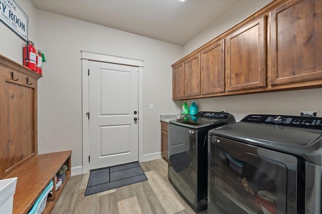 laundry room featuring separate washer and dryer, light hardwood / wood-style flooring, and cabinets