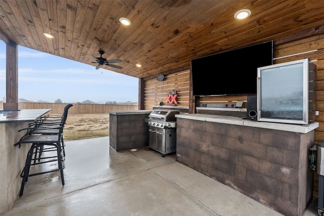 view of patio with a bar, area for grilling, ceiling fan, and exterior kitchen