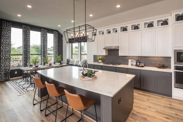 2516 Carretera Dr, Leander, TX 78641 - kitchen with stainless steel appliances, an island with sink, recessed lighting, decorative backsplash, and light wood-style flooring
