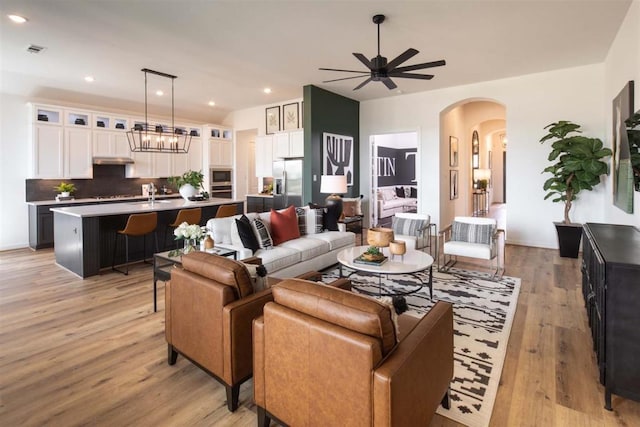 2516 Carretera Dr, Leander, TX 78641 - living area with light wood-style flooring, ceiling fan with notable chandelier, visible vents, arched walkways, and recessed lighting
