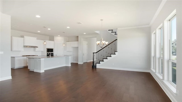 kitchen with dark hardwood / wood-style floors, an island with sink, hanging light fixtures, and white cabinets