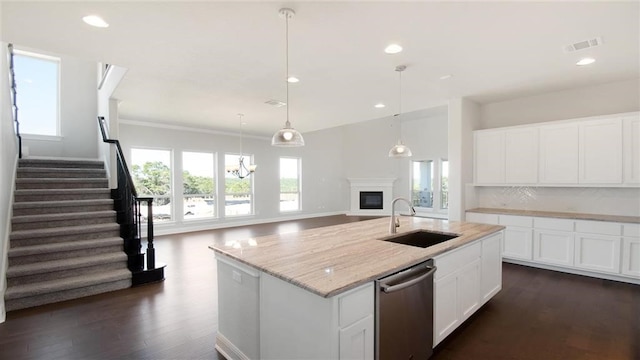 kitchen featuring sink, white cabinets, a kitchen island with sink, stainless steel dishwasher, and light stone counters