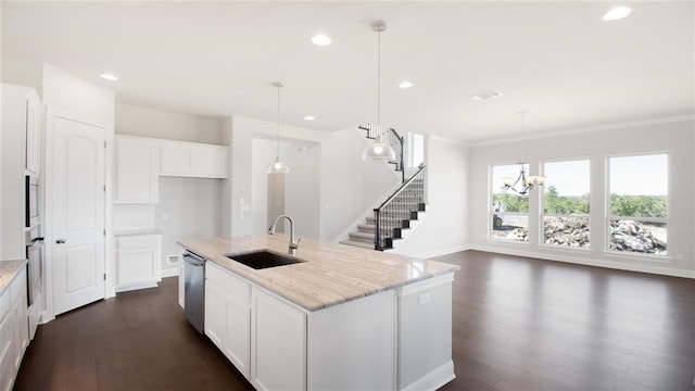 kitchen featuring white cabinetry, sink, stainless steel appliances, light stone countertops, and a center island with sink