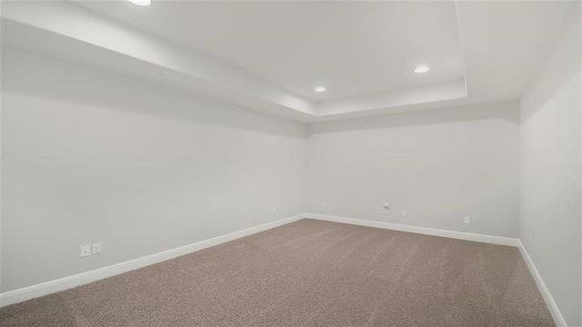 carpeted empty room with a raised ceiling