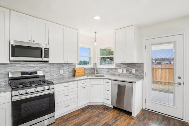 kitchen with sink, appliances with stainless steel finishes, dark hardwood / wood-style flooring, decorative backsplash, and white cabinets