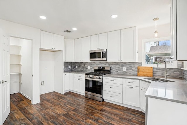 kitchen with decorative light fixtures, white cabinets, and appliances with stainless steel finishes