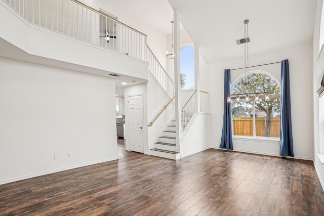 entrance foyer with an inviting chandelier, a towering ceiling, and dark hardwood / wood-style flooring