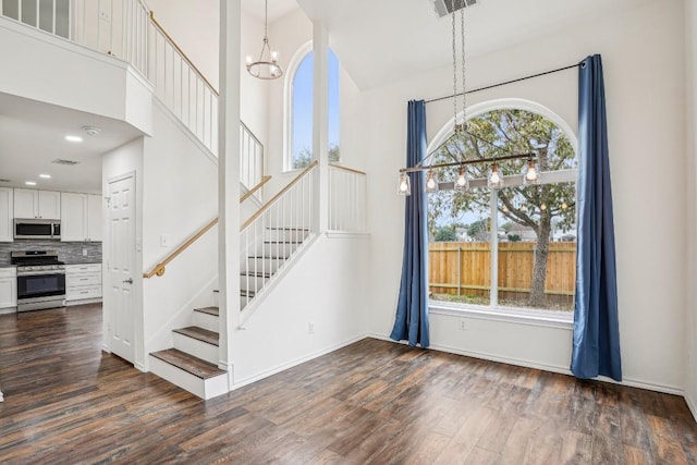 interior space with an inviting chandelier, dark hardwood / wood-style flooring, plenty of natural light, and a high ceiling