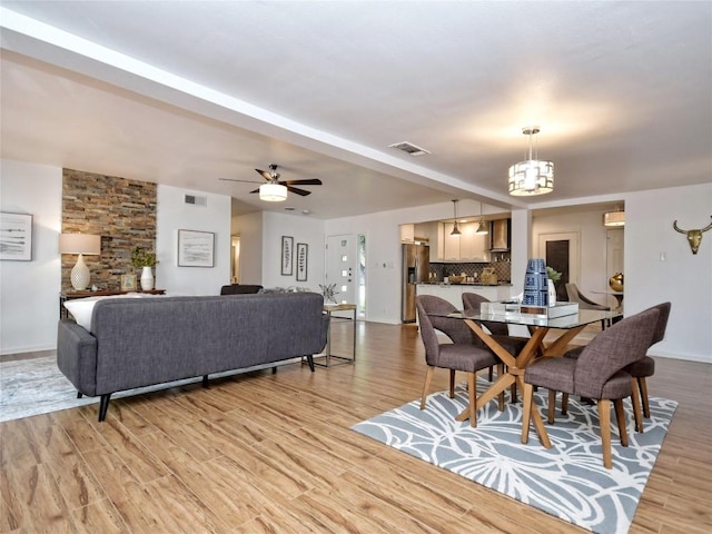 dining room with ceiling fan with notable chandelier and light wood-type flooring