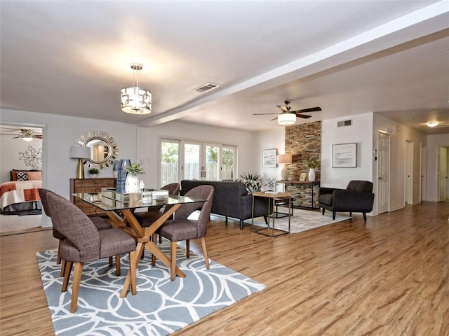 dining room featuring ceiling fan with notable chandelier and light hardwood / wood-style floors