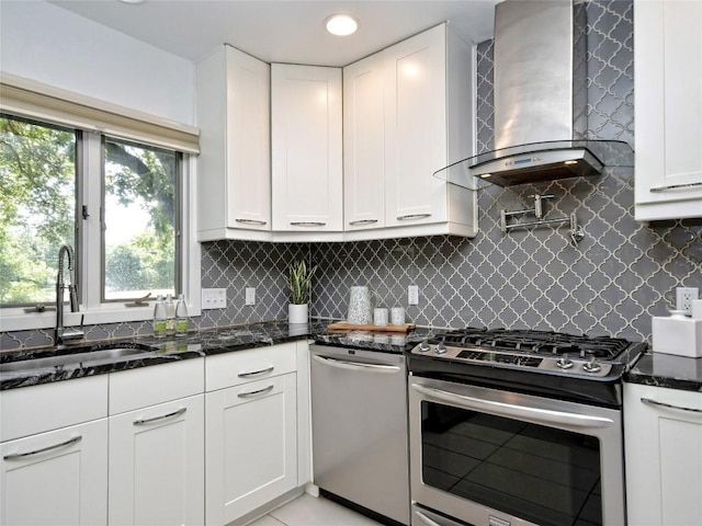 kitchen featuring wall chimney exhaust hood, stainless steel appliances, sink, and white cabinets