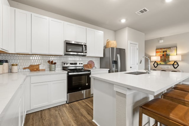 kitchen featuring sink, a breakfast bar area, a kitchen island with sink, stainless steel appliances, and white cabinets