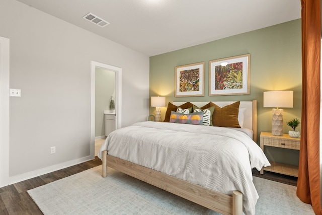 bedroom with connected bathroom and dark hardwood / wood-style floors