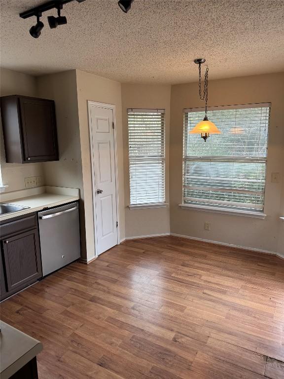 kitchen featuring dishwasher, hanging light fixtures, dark brown cabinetry, light hardwood / wood-style floors, and a textured ceiling