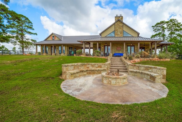 back of property with an outdoor fire pit and a lawn