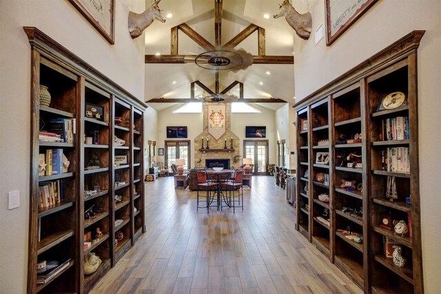 interior space featuring hardwood / wood-style flooring, a large fireplace, ceiling fan, and a high ceiling