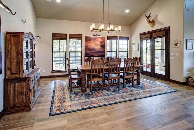 dining space with french doors, a notable chandelier, high vaulted ceiling, and light wood-type flooring