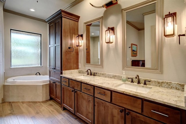 bathroom featuring ornamental molding, wood-type flooring, vanity, and tiled tub