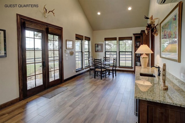 dining room featuring sink, wood-type flooring, high vaulted ceiling, and french doors