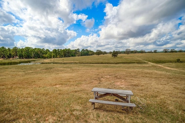 view of property's community with a rural view, a lawn, and a water view