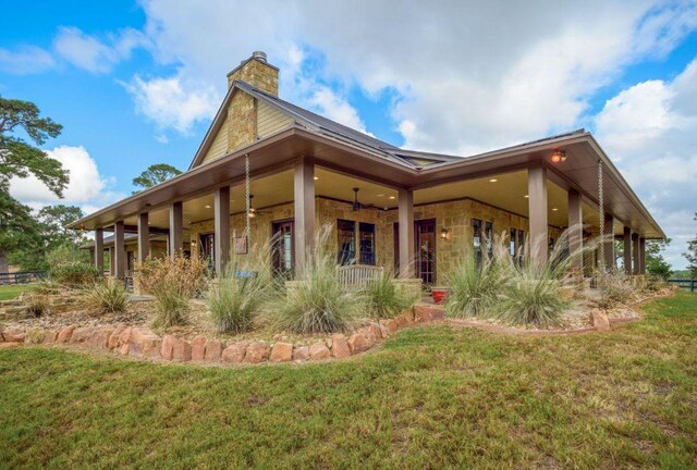 0000 Gotier Trace Rd, Smithville, TX 78957 - back of house featuring a chimney, a yard, ceiling fan, and stone siding