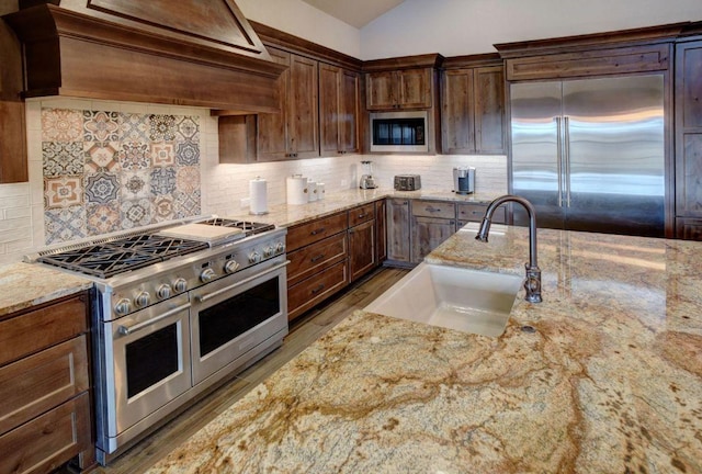 0000 Gotier Trace Rd, Smithville, TX 78957 - kitchen featuring built in appliances, a sink, custom exhaust hood, light stone countertops, and wood finished floors