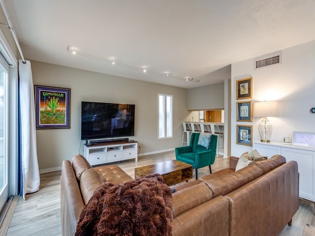 living room with rail lighting and light hardwood / wood-style floors