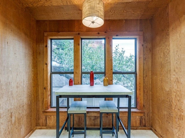 dining space with wooden ceiling, a healthy amount of sunlight, and wood walls