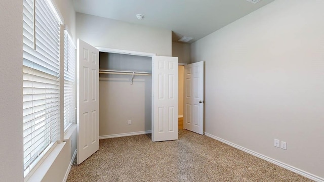 unfurnished bedroom featuring light carpet and a closet