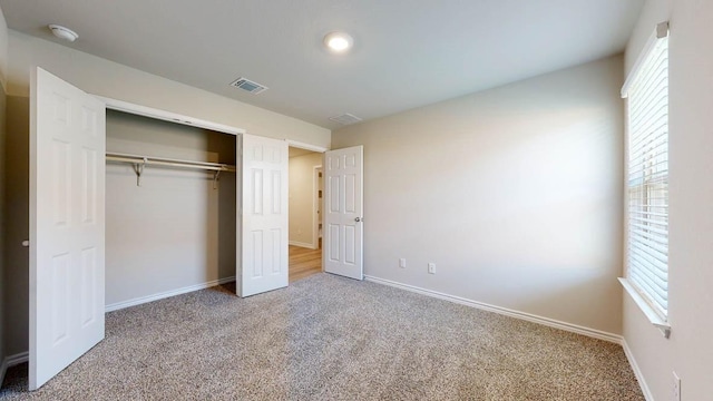 unfurnished bedroom with multiple windows, a closet, and carpet