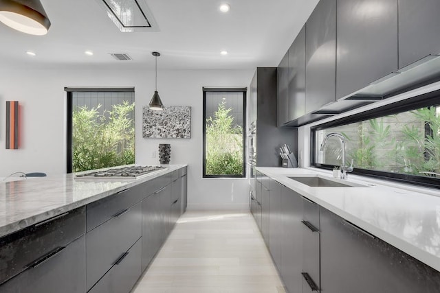 kitchen featuring stainless steel gas cooktop, visible vents, gray cabinetry, a sink, and modern cabinets