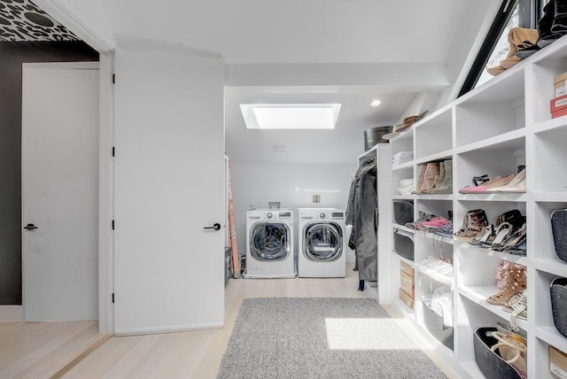 laundry area featuring a skylight, laundry area, washing machine and dryer, and wood finished floors