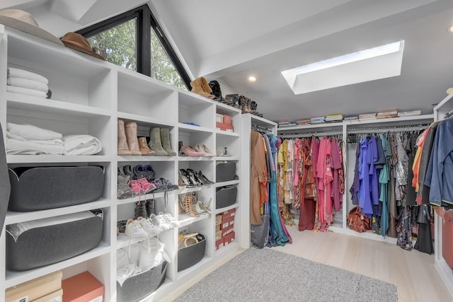 walk in closet with a skylight and wood finished floors