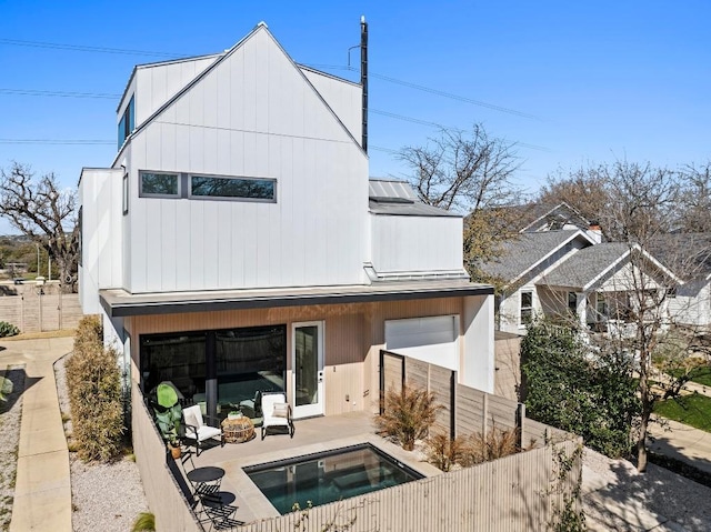 rear view of property featuring a standing seam roof, a fenced backyard, metal roof, and a patio