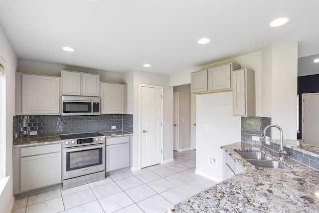 kitchen featuring appliances with stainless steel finishes, light stone countertops, and sink