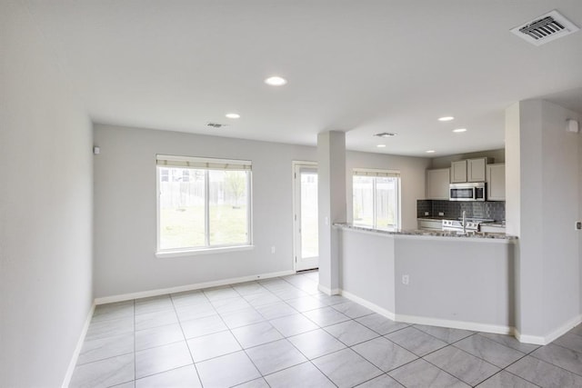 kitchen featuring light stone counters, light tile patterned floors, decorative backsplash, and stainless steel appliances