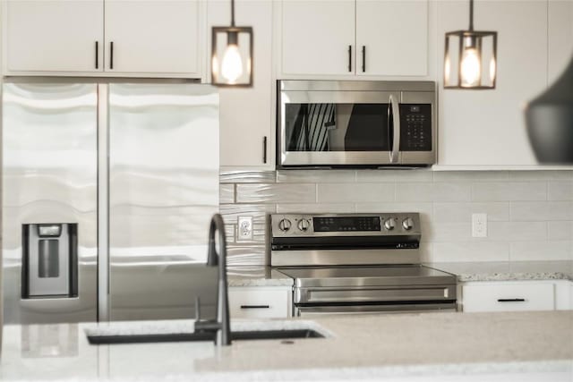 kitchen with light stone counters, stainless steel appliances, white cabinets, tasteful backsplash, and pendant lighting