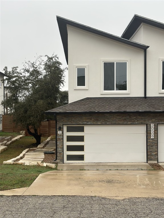 view of side of home featuring a garage, concrete driveway, roof with shingles, and stucco siding