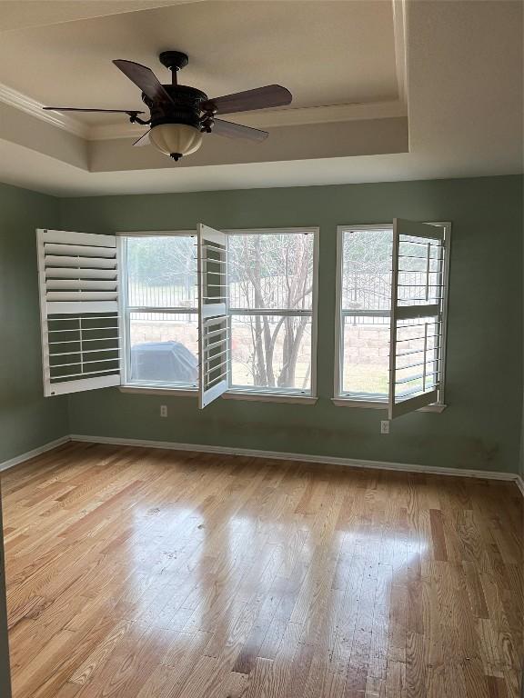 spare room featuring crown molding, ceiling fan, light hardwood / wood-style floors, and a tray ceiling