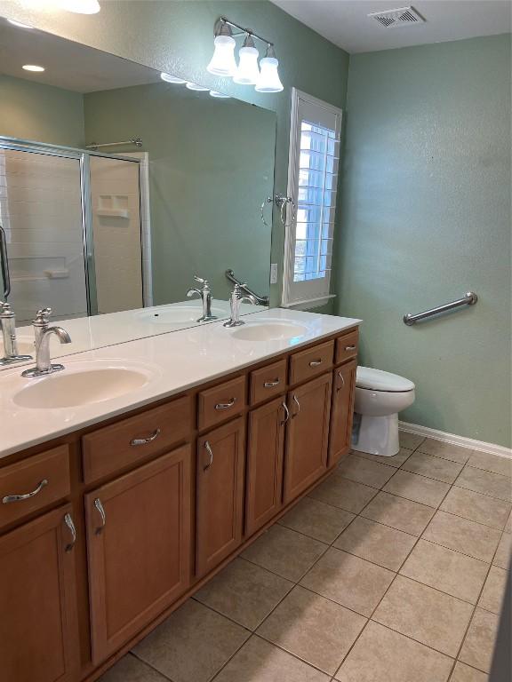 bathroom featuring vanity, toilet, tile patterned flooring, and a shower with door