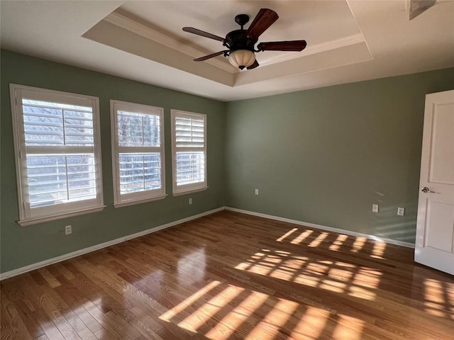 empty room featuring a tray ceiling, ornamental molding, ceiling fan, and hardwood / wood-style flooring